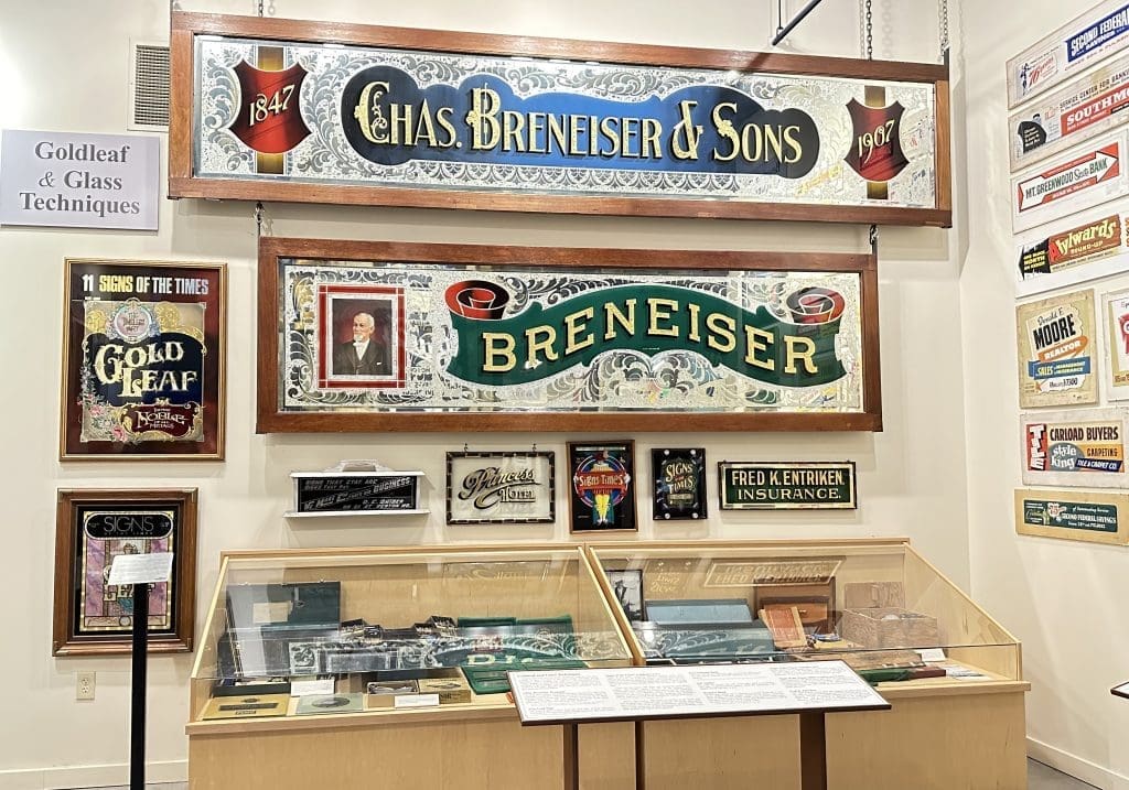 Vintage brewery signs displayed on a museum wall.