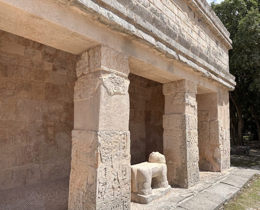 Ancient stone structure with carved pillars and a seated statue.