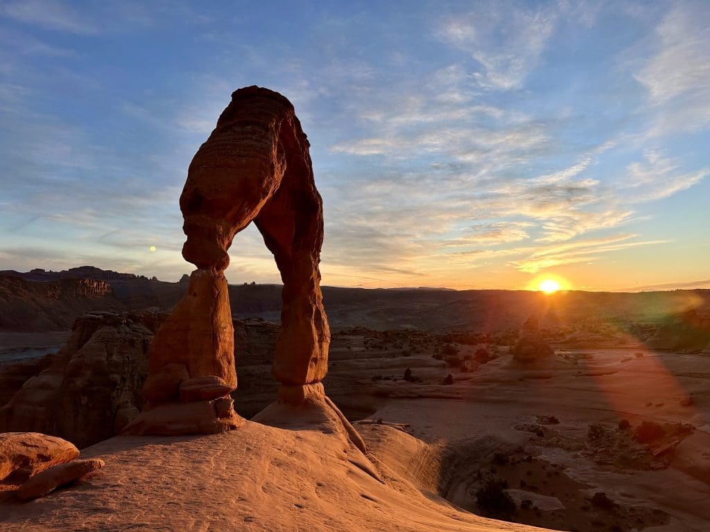 Natural rock arch at sunset in a desert landscape.