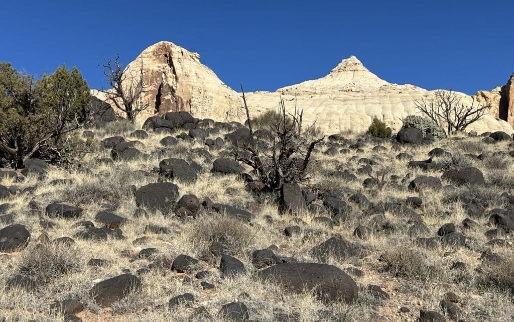 Navajo Dome (point on left) rises above the black boulders on the hillside