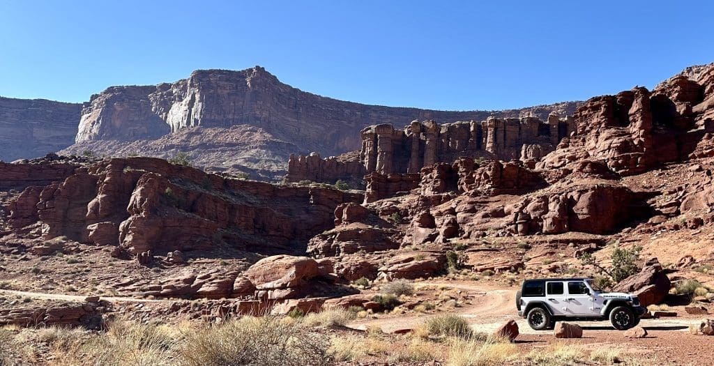 A rugged canyon landscape with a vehicle in the foreground.
