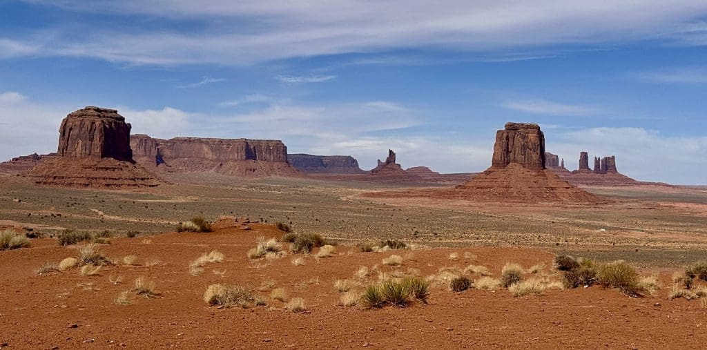 A vast desert landscape with rock formations under a blue sky.