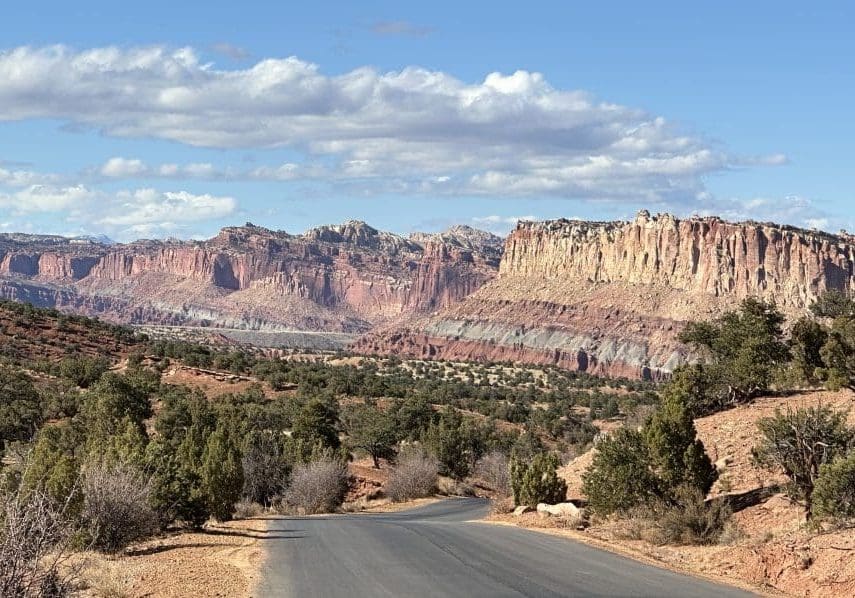 A winding road leading through a desert landscape with rocky cliffs.